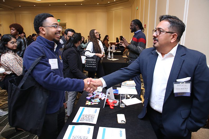 two men shaking hands over table at a conference