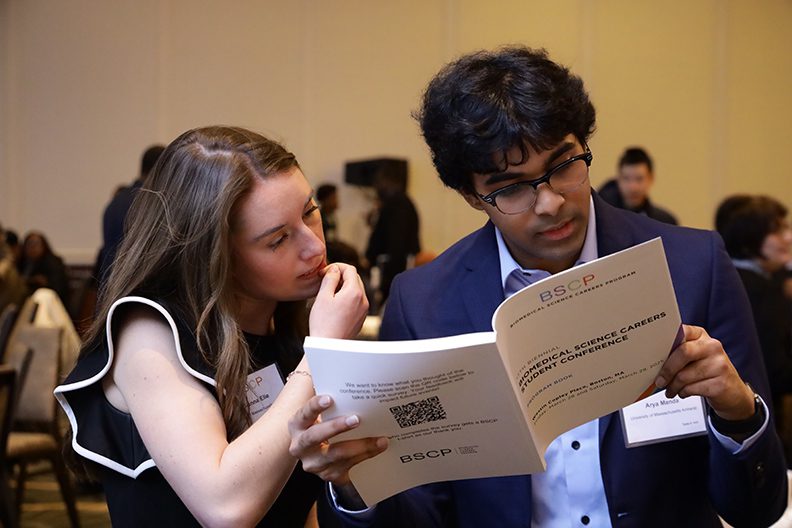two students look at event program book for student conference