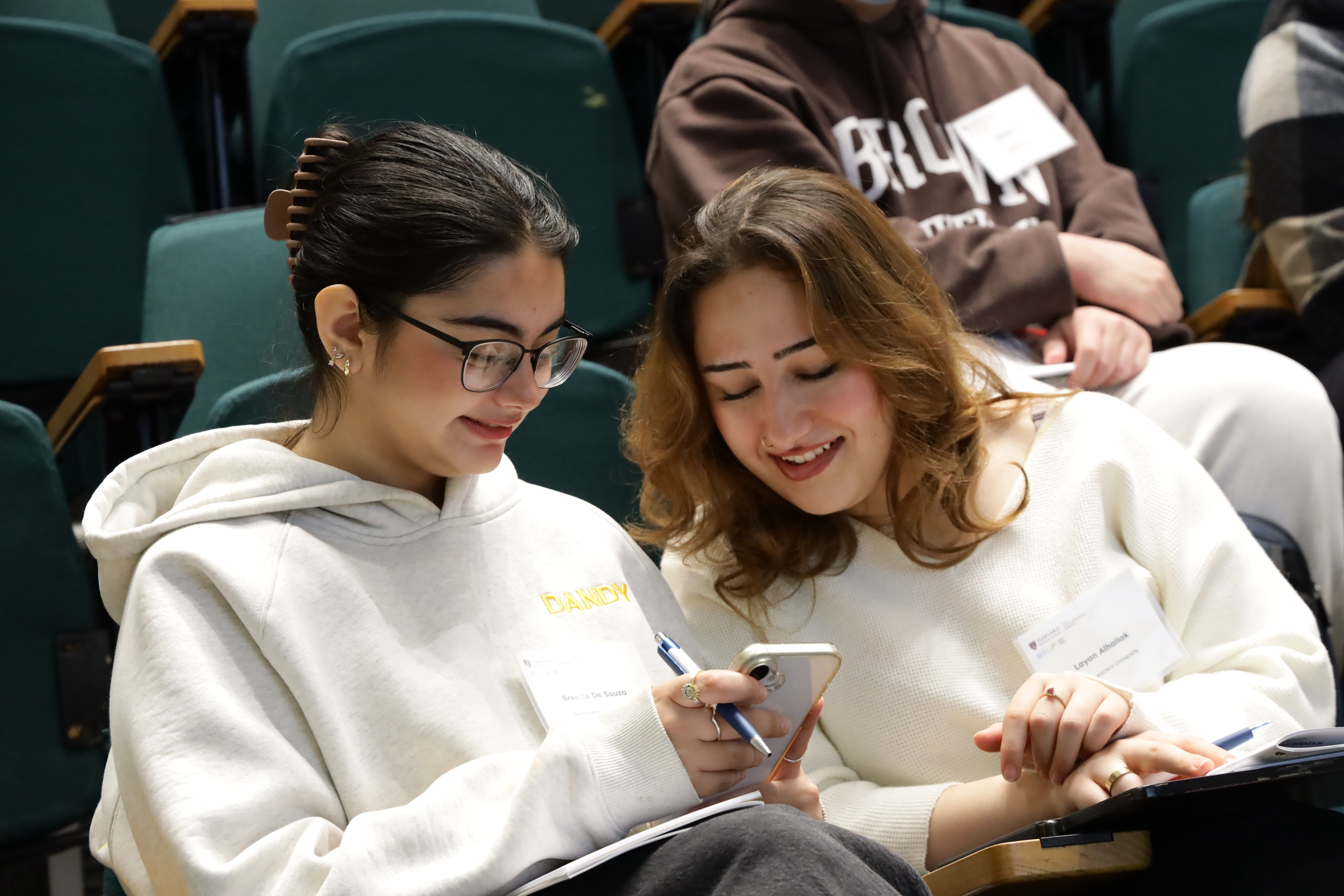 two young women, one is looking at something the other is showing her on her phone